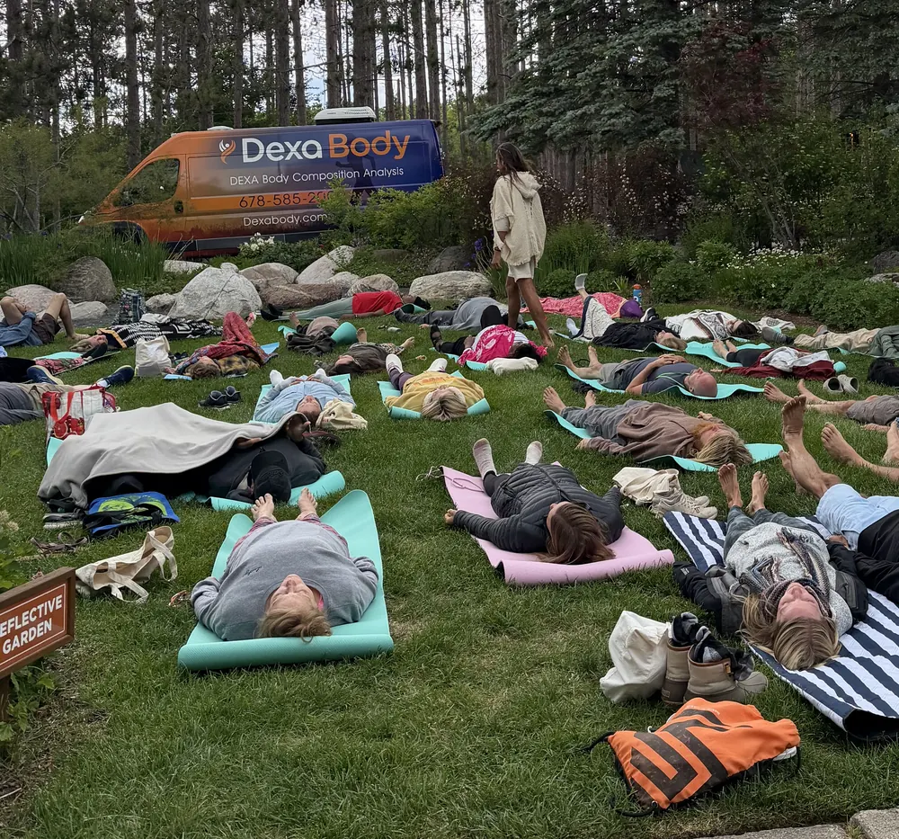 The Dexa Body mobile scanning van parked behind guests resting on mats on the lawn at the 2026 Michigan retreat