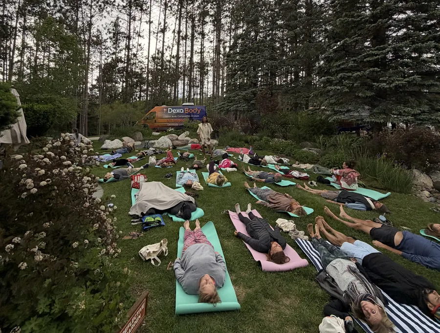 Guests resting on the lawn under a big sky with the Dexa Body van parked beyond the trees