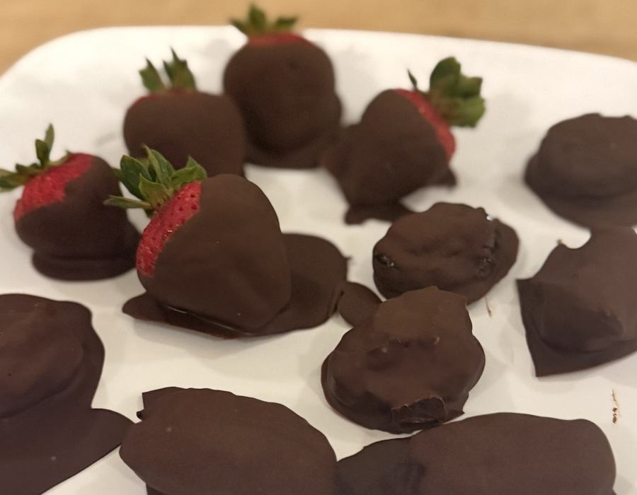 Chocolate-dipped strawberries and almond butter date truffles arranged on a white plate