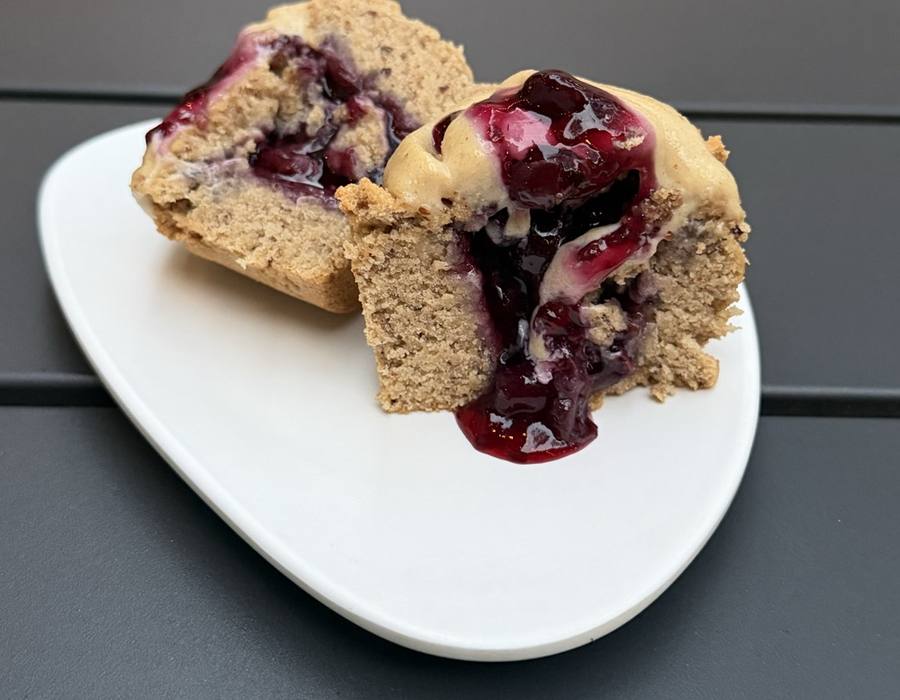 A cupcake split open with berry filling running out