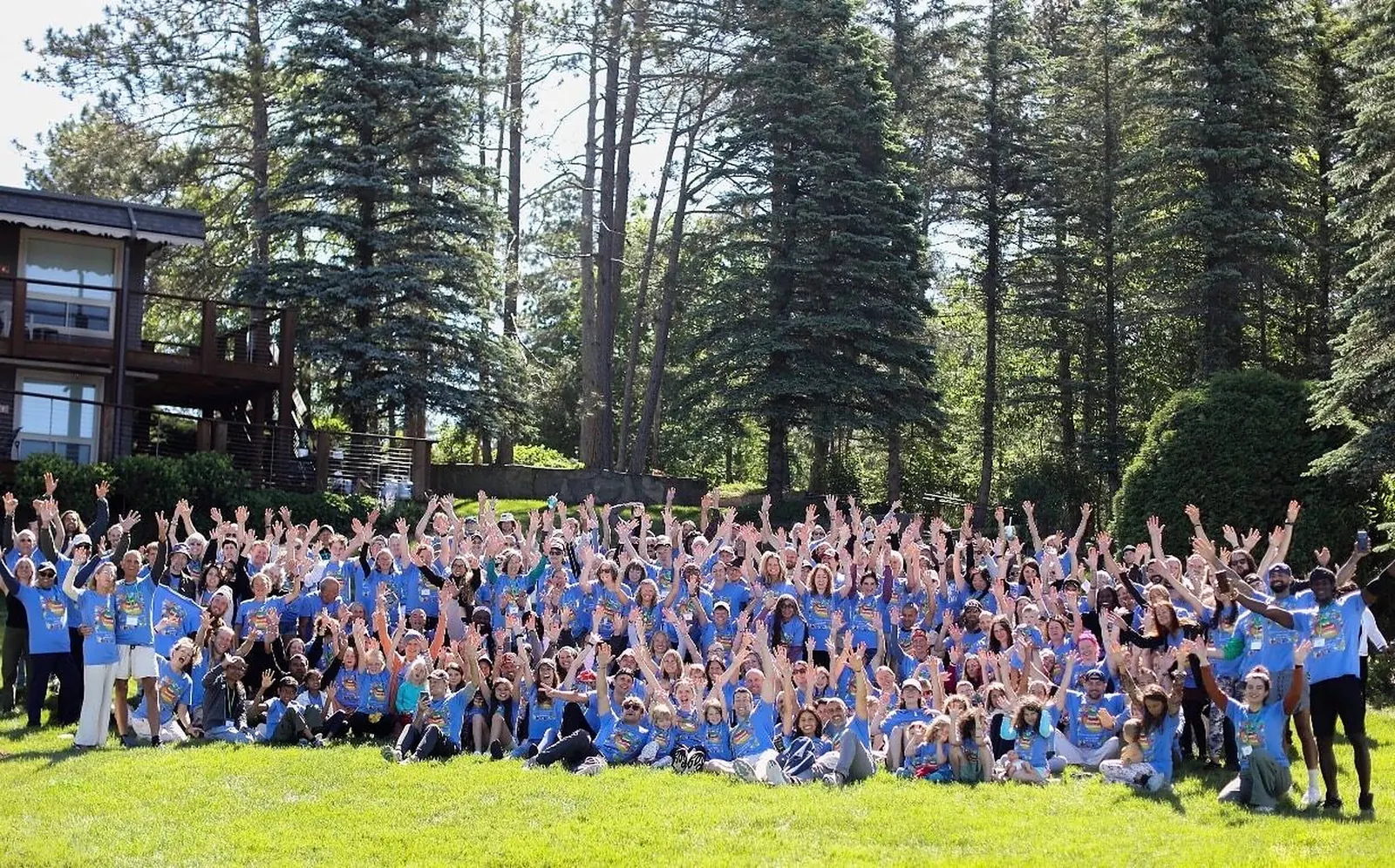 Hundreds of guests in blue retreat shirts with their hands raised for the group photo at the 2026 Michigan retreat