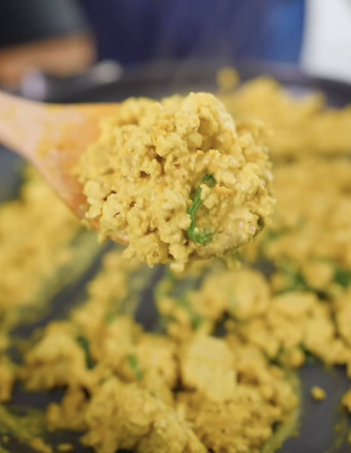 A wooden spoon lifting gluten-free mac and cheese out of the pan