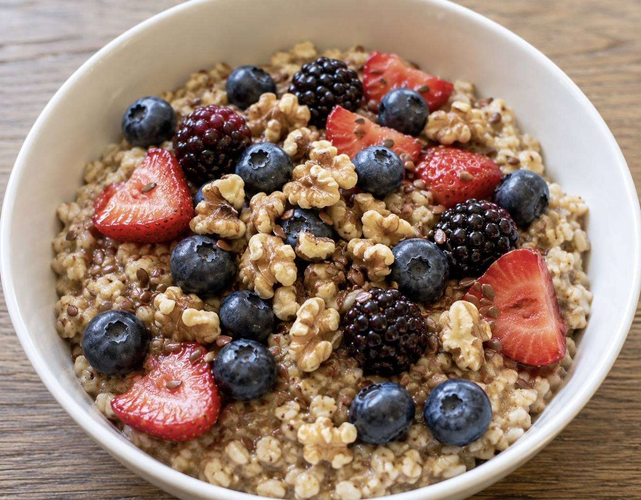 A bowl from the oatmeal bar topped with strawberries, blueberries, blackberries and walnuts