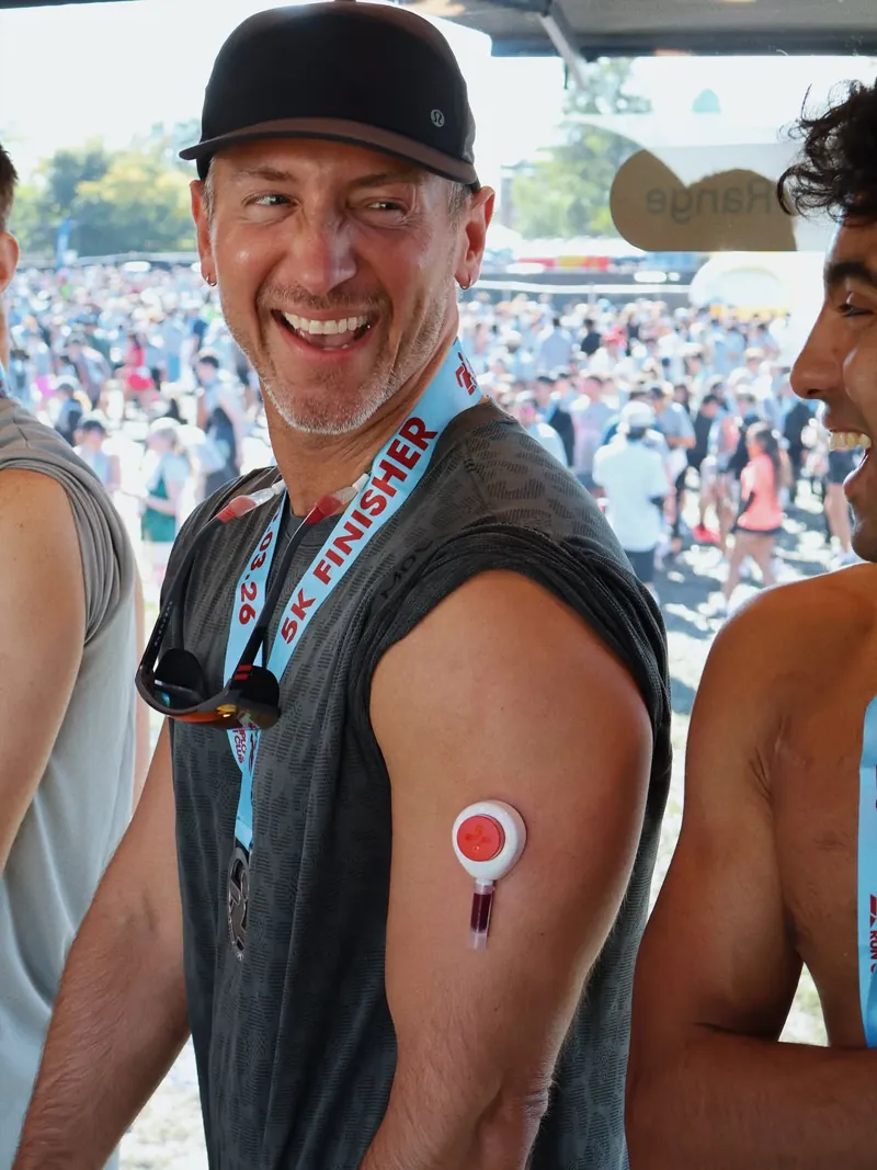 A smiling man wearing the Rythm collection device on his upper arm