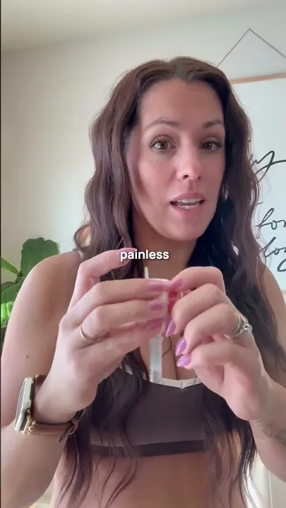 A woman holding the Rythm blood collection device, explaining it is painless